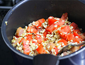 野菜、押し麦、調味料、トマトを鍋に加えた様子