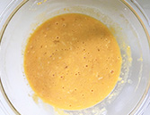 ボウルに、卵、とろけるチーズ、牛乳、顆粒コンソメ、塩、胡椒、薄力粉を混ぜ合わせる様子
