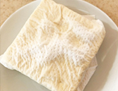 木綿豆腐をキッチンペーパーで包み、電子レンジで加熱する様子。